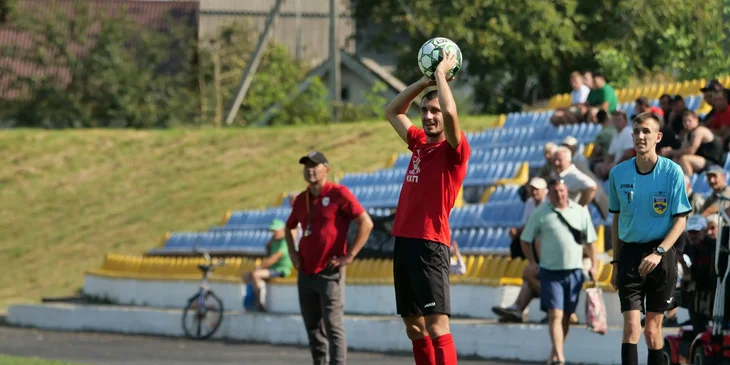A coach about to throw a ball onto the field.