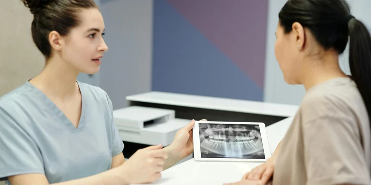 An associate dentist showing a dental X-ray to a patient.