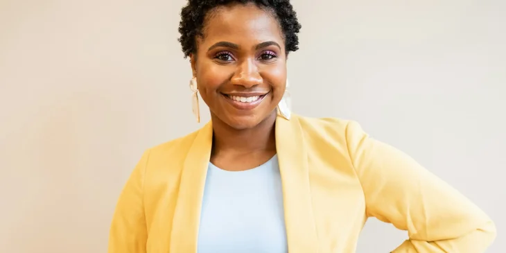A woman in yellow blazer smiling.
