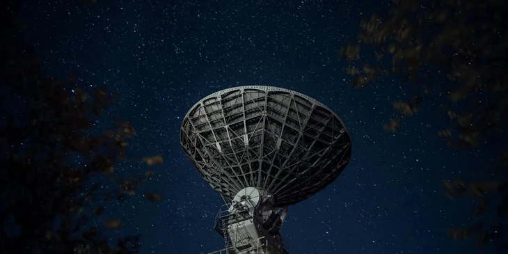 A radio telescope beneath the starry night sky.