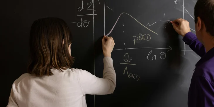 Astrophysicists doing mathematical graphs on the board.