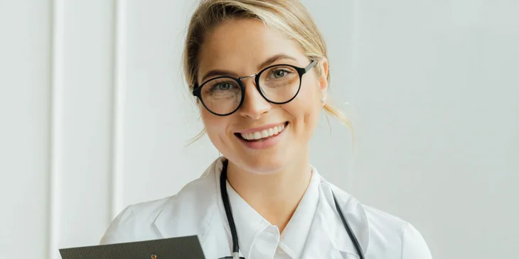 A doctor wearing glasses and smiling.
