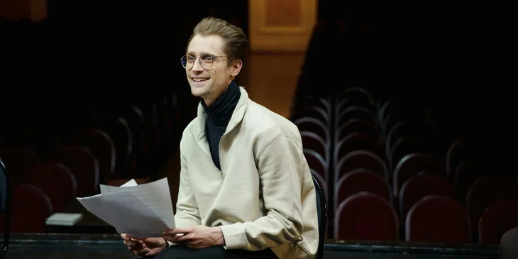A man sitting on a chair holding a script.