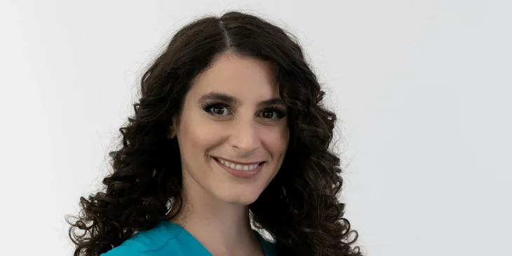 A woman in a blue shirt smiling.