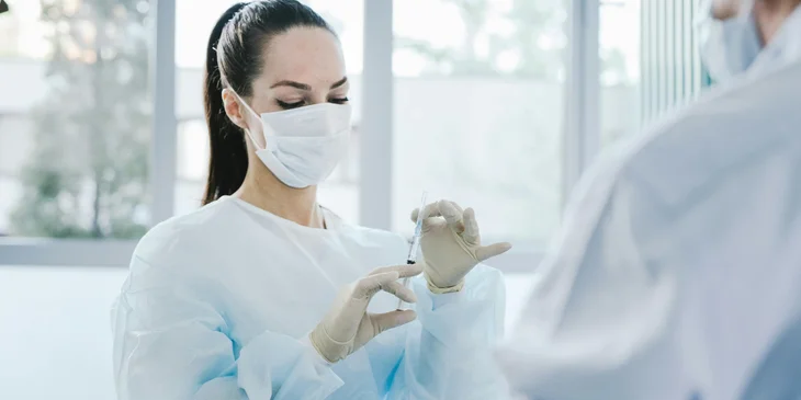 A medical professional holding a syringe.
