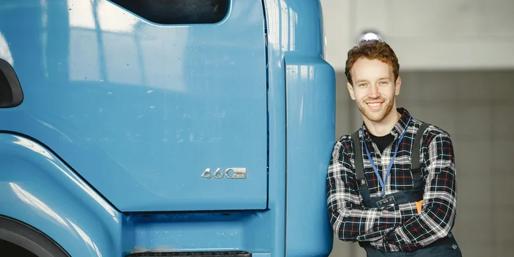 Ein Angestellter lehnt sich an einen Lastkraftwagen an.