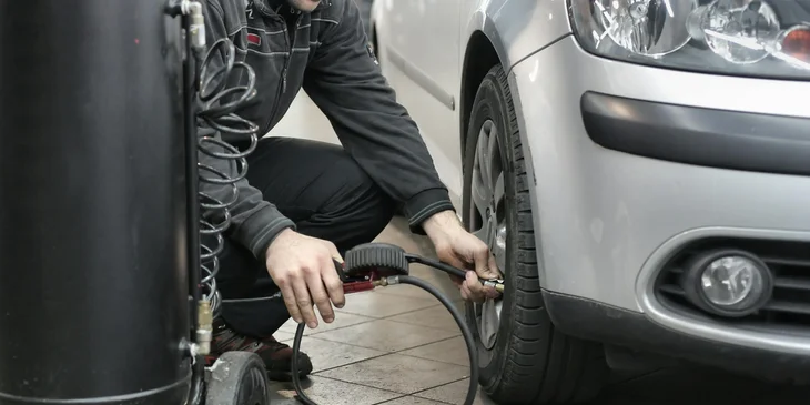 A mechanic putting air in the tire.