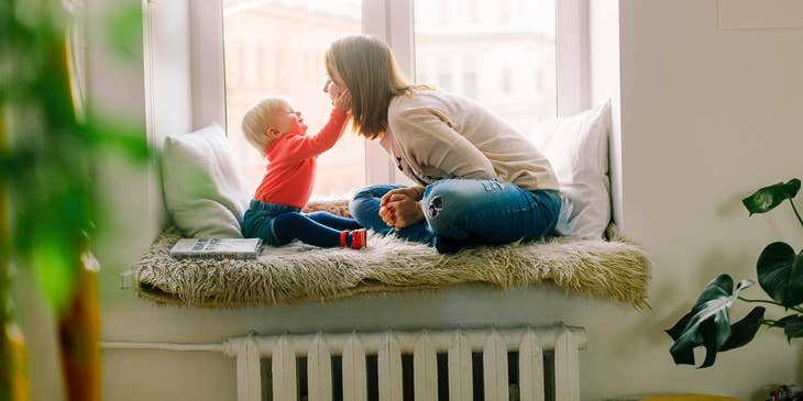 Babysitter playing with a baby by a window