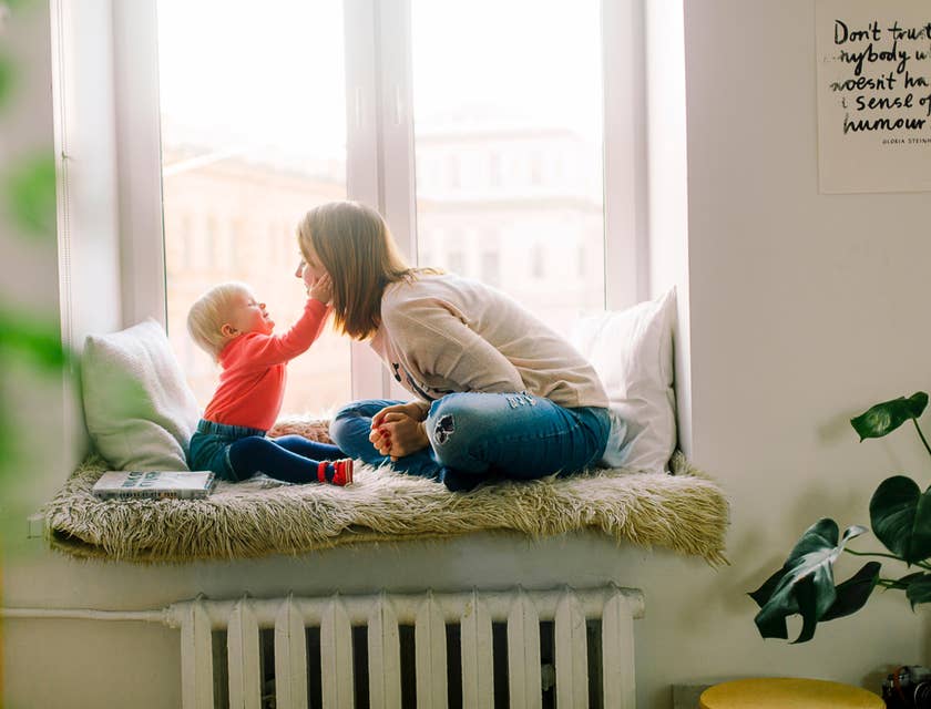 Babysitter playing with a baby by a window