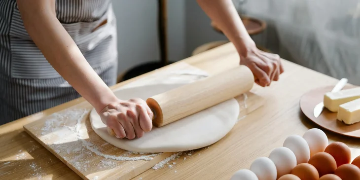 A baker rolling a pin over dough.