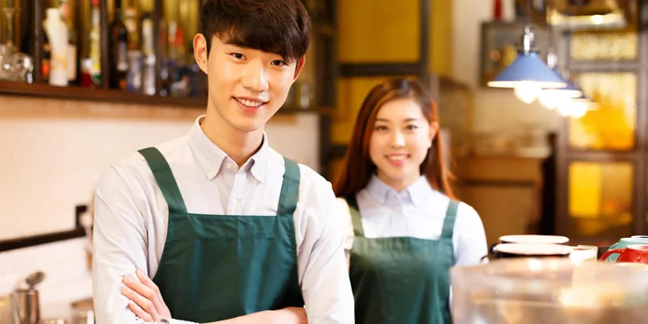 Two baristas smiling.