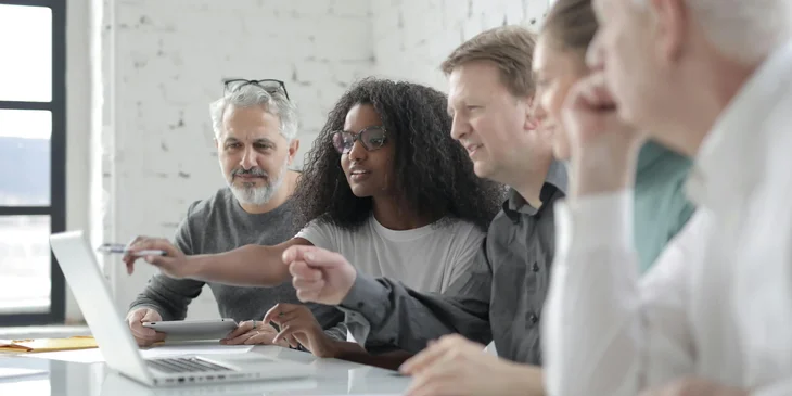 Coworkers discussing a project while looking at a laptop.