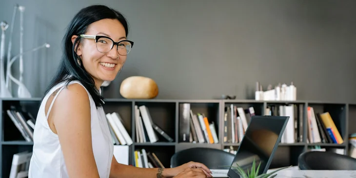 A smiling woman working on her laptop.