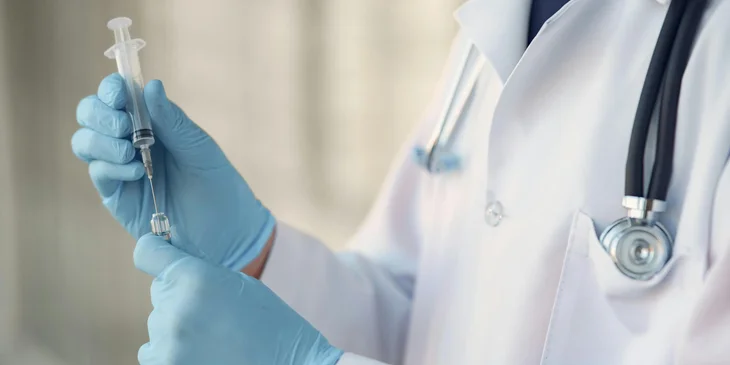 A healthcare professional preparing a syringe to administer the vaccine.
