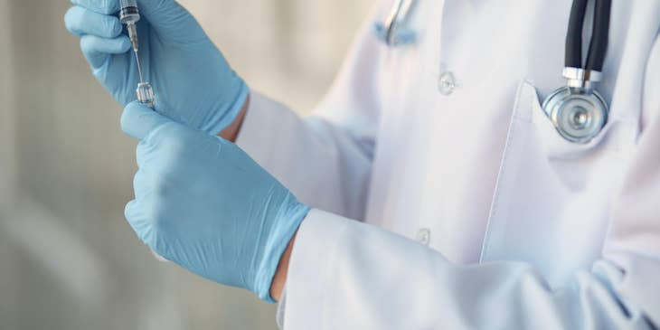 A healthcare professional preparing a syringe.