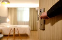 Un profesional de la hostelería abriendo la puerta de una habitación de hotel.
