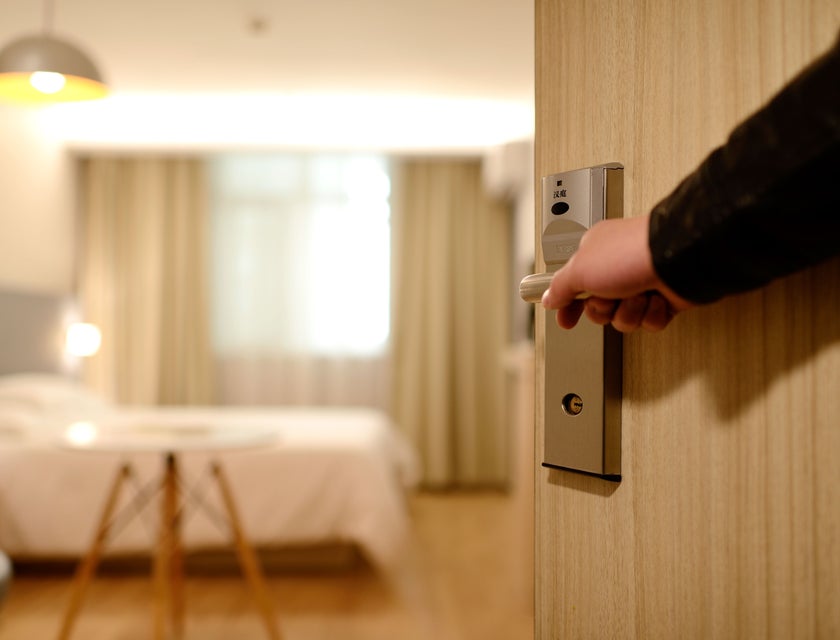 A hospitality professional opening a hotel room door.