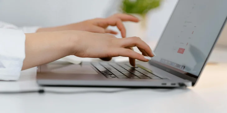 Hands typing on a laptop keyboard.