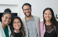 Vier lächelnde Mitarbeiter stehen in einem Büro.