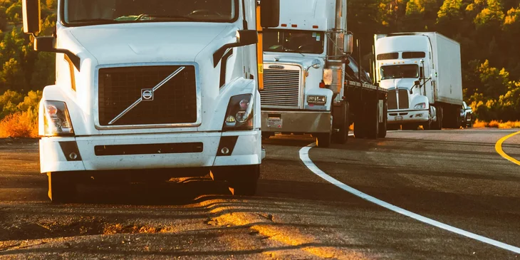 Una fila de trailers a la orilla de la carretera, conducidos por operadores.