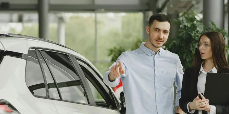 Vendedora de autos con un cliente, en una agencia automotriz.