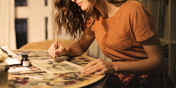 Una ilustradora pintando un diseño sobre una hoja de papel.