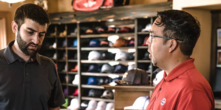 Un representante de ventas vendiendo palos de golf a un cliente.