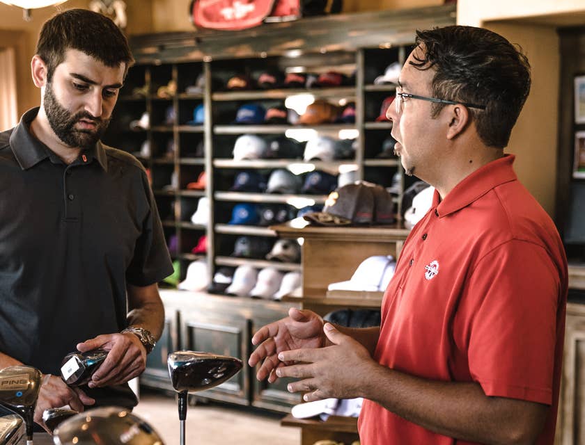 Un representante de ventas vendiendo palos de golf a un cliente.