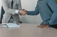 Un entrevistador de trabajo y una candidato dándose la mano después de una entrevista exitosa.