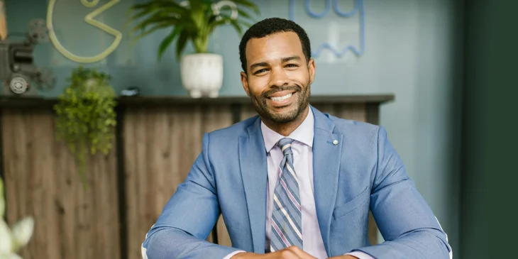 A man smiling at his desk.