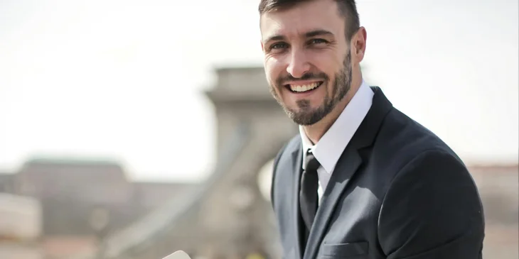 A man in black suit jacket smiling.