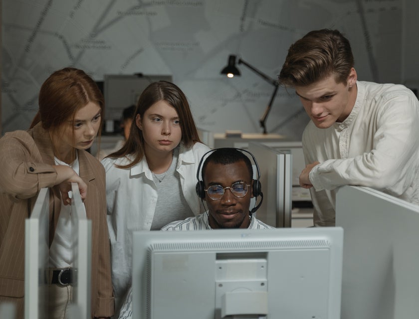 A call center trainer showing co-workers an important document on a computer,