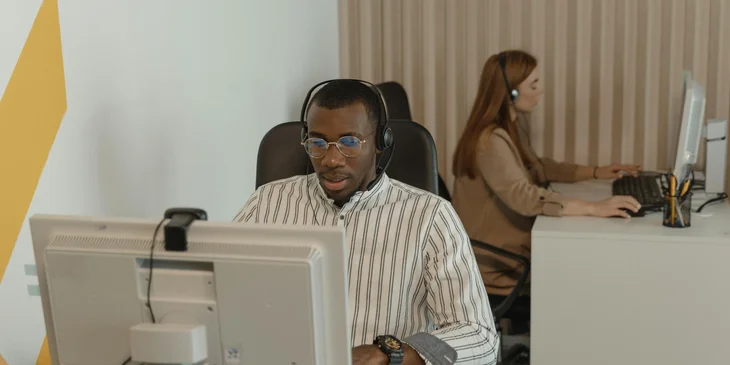 The call center representatives wearing headsets and looking at their computers.