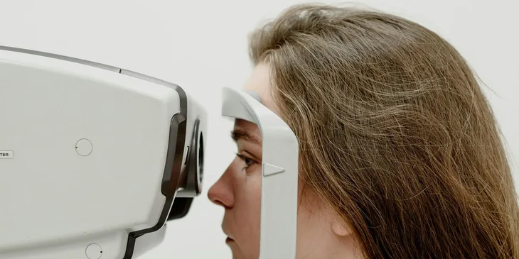 A woman examining her vision in a hospital with modern apparatus.