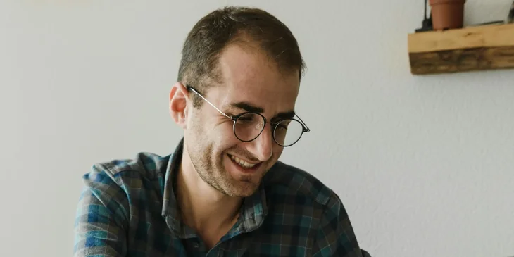 A man in blue plaid shirt wearing a black framed glasses.