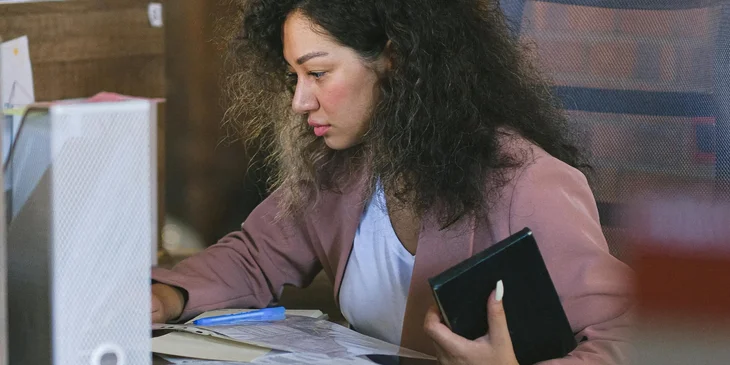 A female employee reading documents during work in an office.