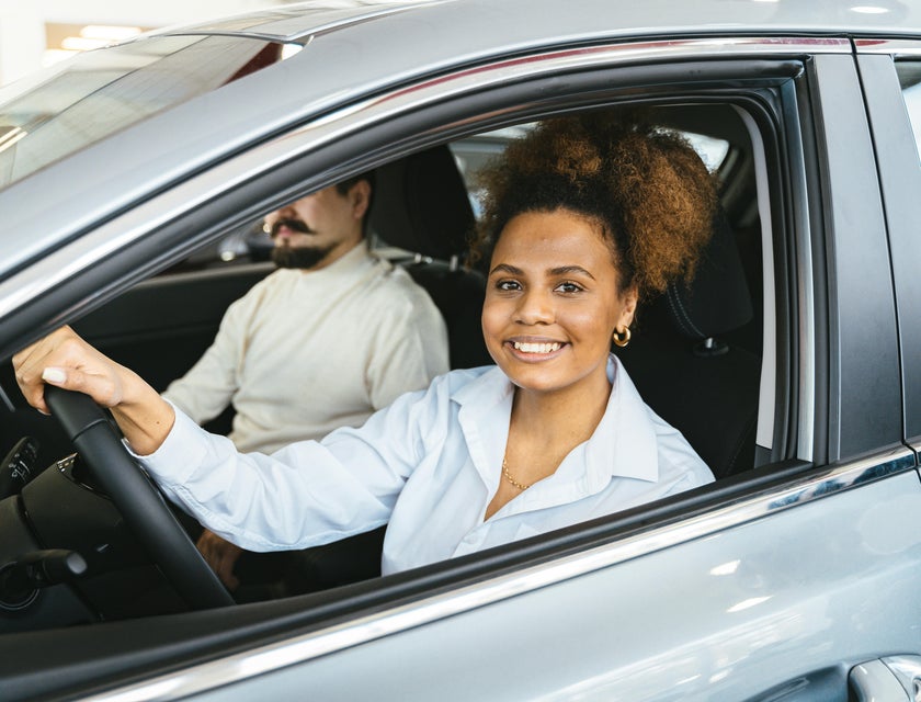 Una donna sorridente al volante di una macchina aziendale.