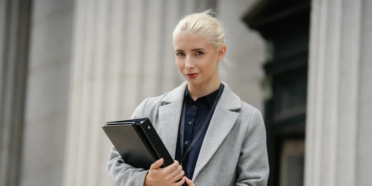 A smartly dressed woman looking toward a camera.