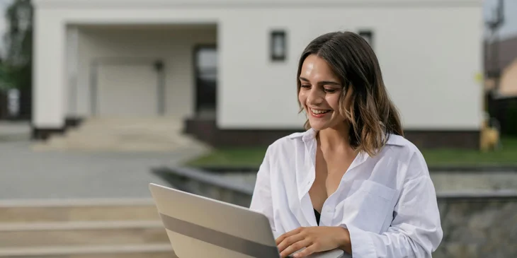 A woman in a white shirt using a laptop.