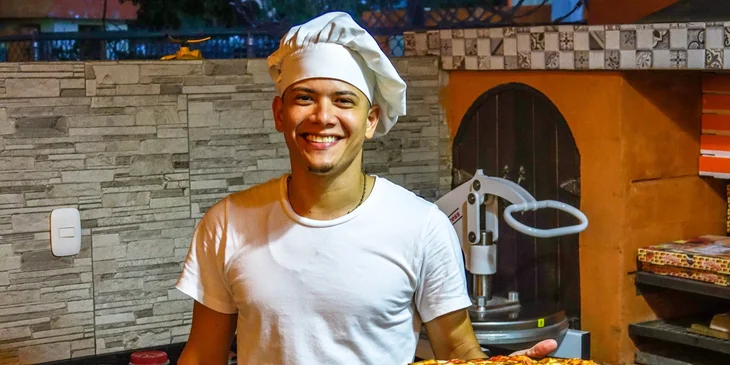 A pizza chef holding a newly baked pizza.