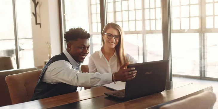 Business partners gathering together in a modern workspace with a laptop.