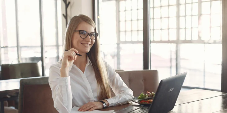 A cheerful woman thinking of new ideas in front of her laptop.
