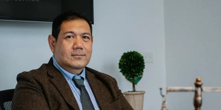 A lawyer in formal outfit sitting in an office.