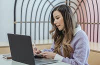 Un gerente de casos clínicos mirando su laptop y escribiendo en un cuaderno.