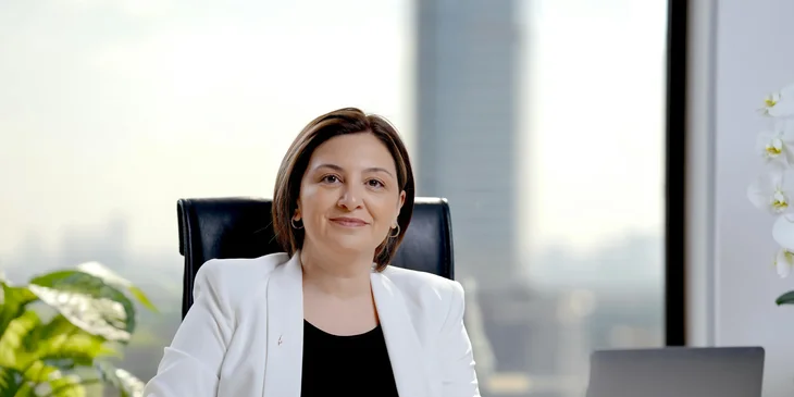 A woman in a white suit sitting in an office.