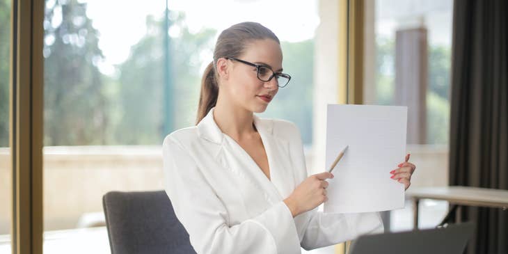A woman holding a code of ethics document and pointing to it.