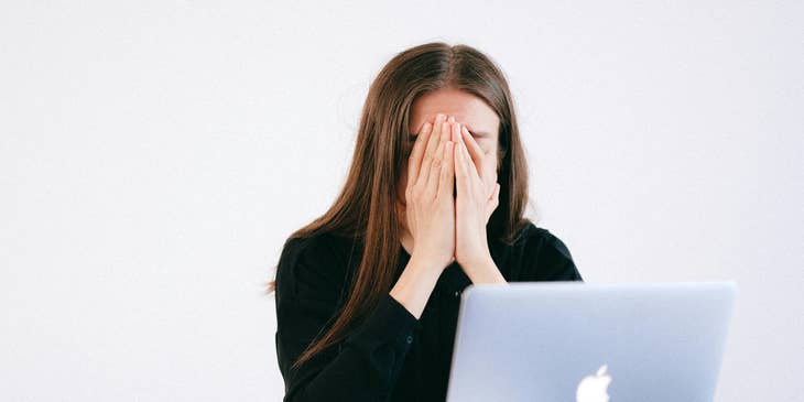 Una mujer sentada frente a una computadora portátil después de haber sido despedida.