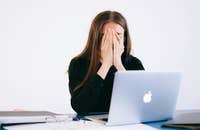 Una mujer sentada frente a una computadora portátil después de haber sido despedida.