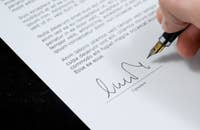 Un hombre firmando una carta de recomendación.