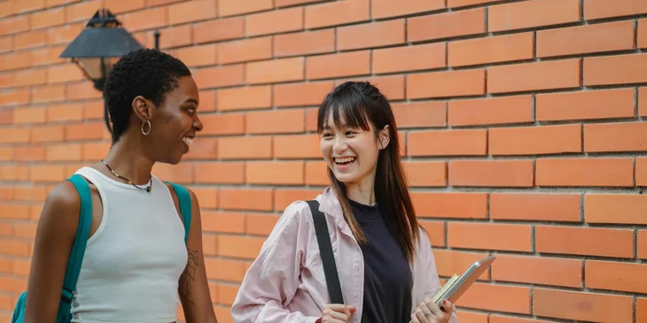 Two college students chatting while walking in a school campus.